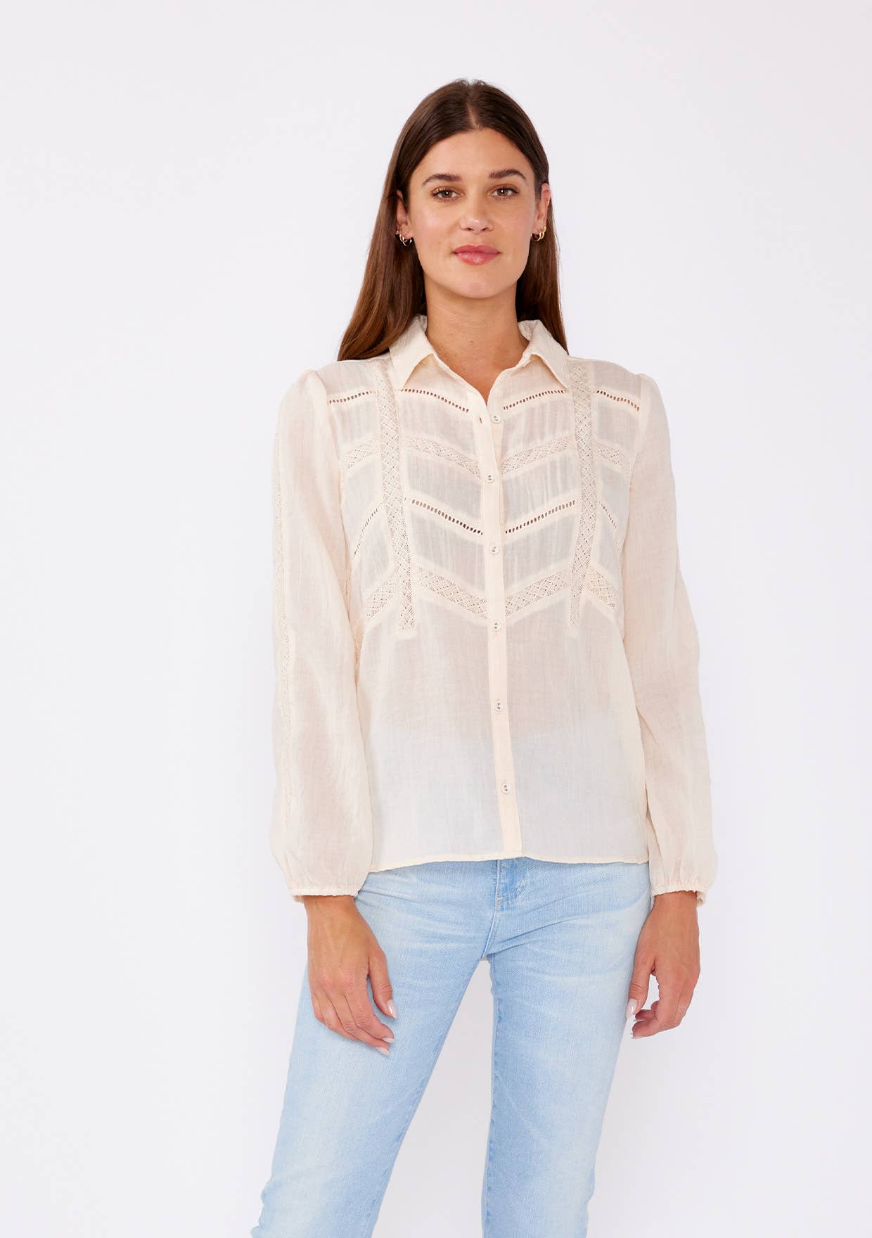 Woman wearing a cream Crinkled Lace Long Sleeve Button Down Blouse paired with light blue jeans against white background