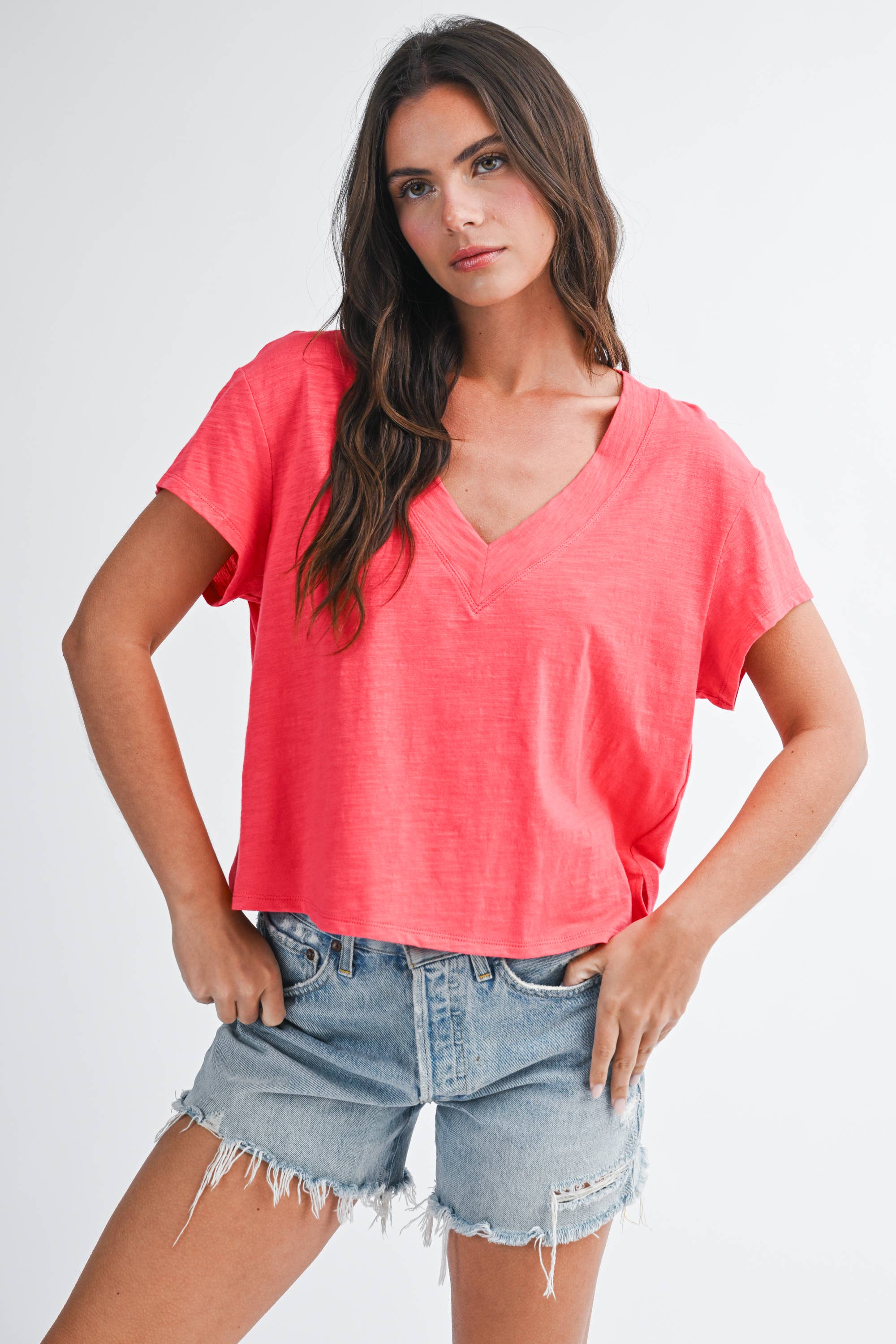 Woman wearing 8281DK Til V-Neck Baby Top: Coral / Contemporary / S with casual denim shorts, hands on hips.