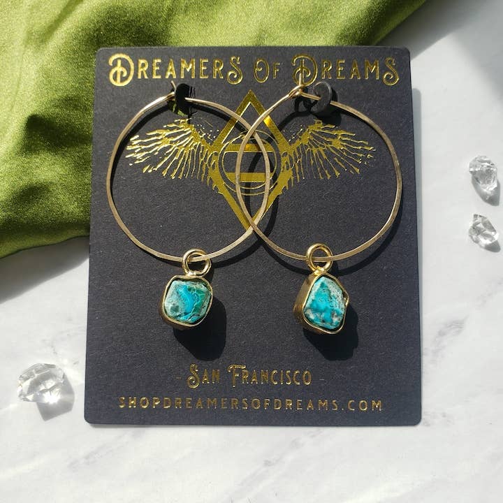 The Dreamers of Dreams 14k gold fill 1.5 Gemstone Hoops feature blue-green stone charms and come displayed on a branded card—ideal natural stone earrings for everyday wear.
