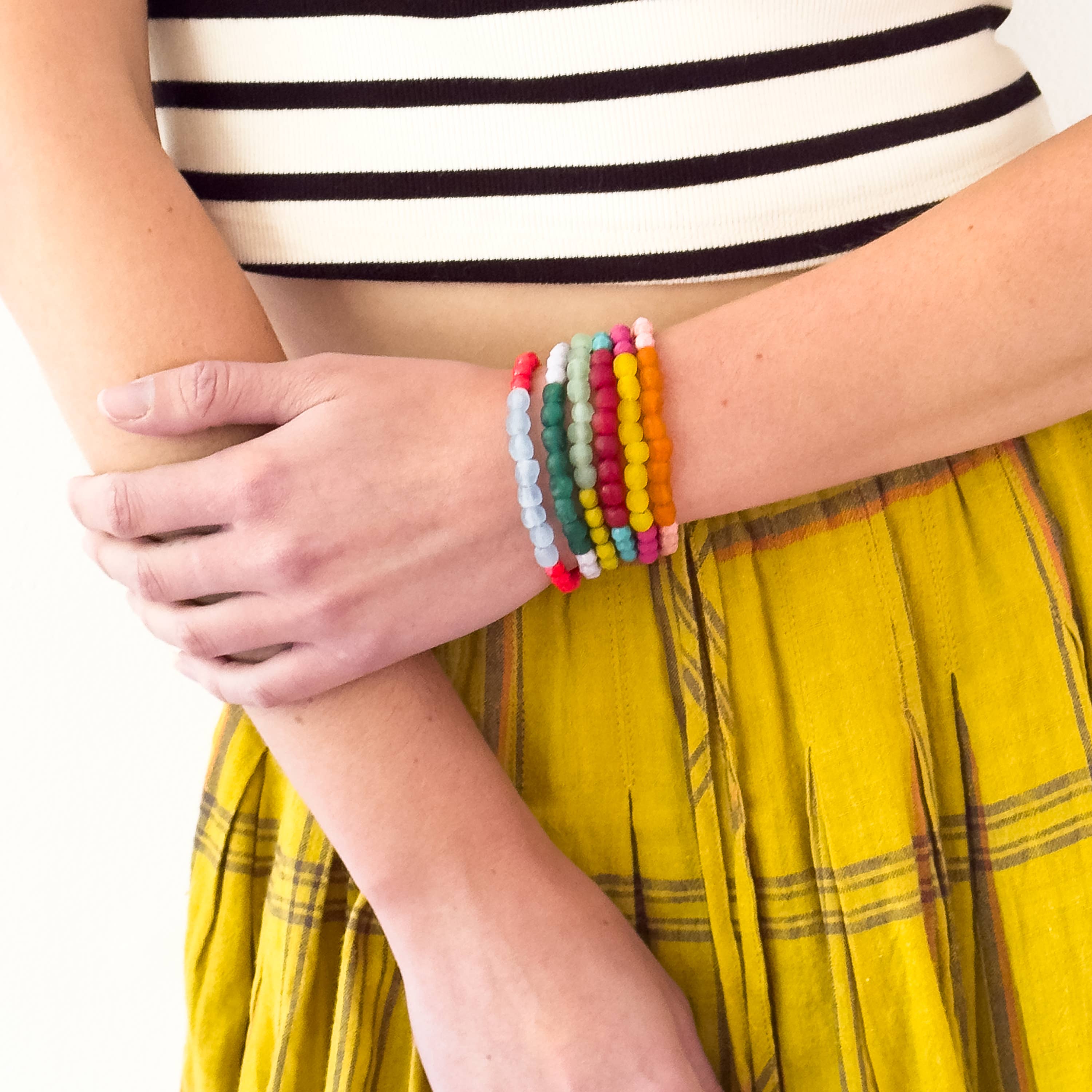 Woman wearing a stack of colorful beaded bracelets featuring the Multicolor Recycled African Glass And Mixed Bead Bracelet style