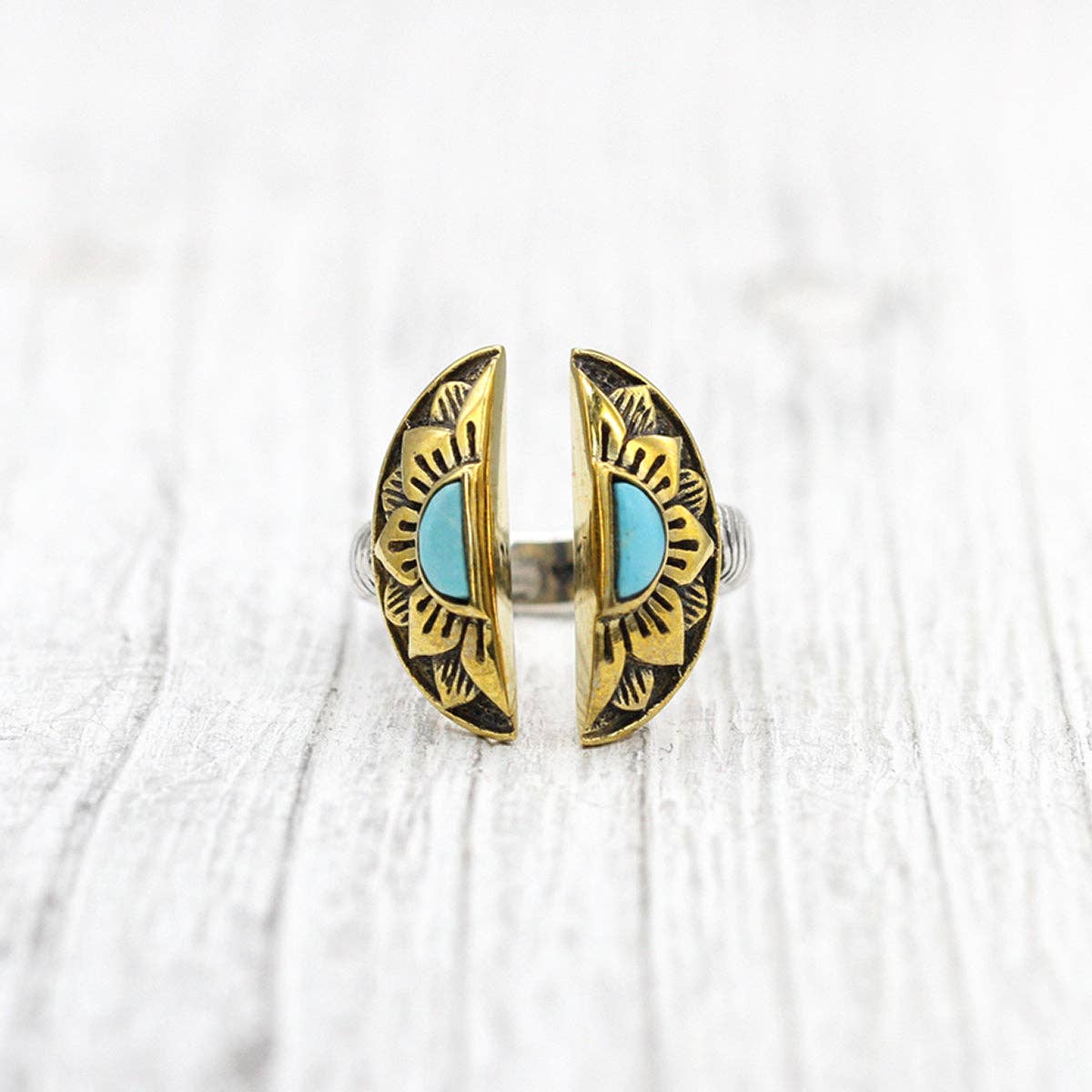 The bahgsu jewels Natural Mystic Ring - Turquoise features twin crescent shapes with turquoise center stones and black engravings, shown on a light textured surface.