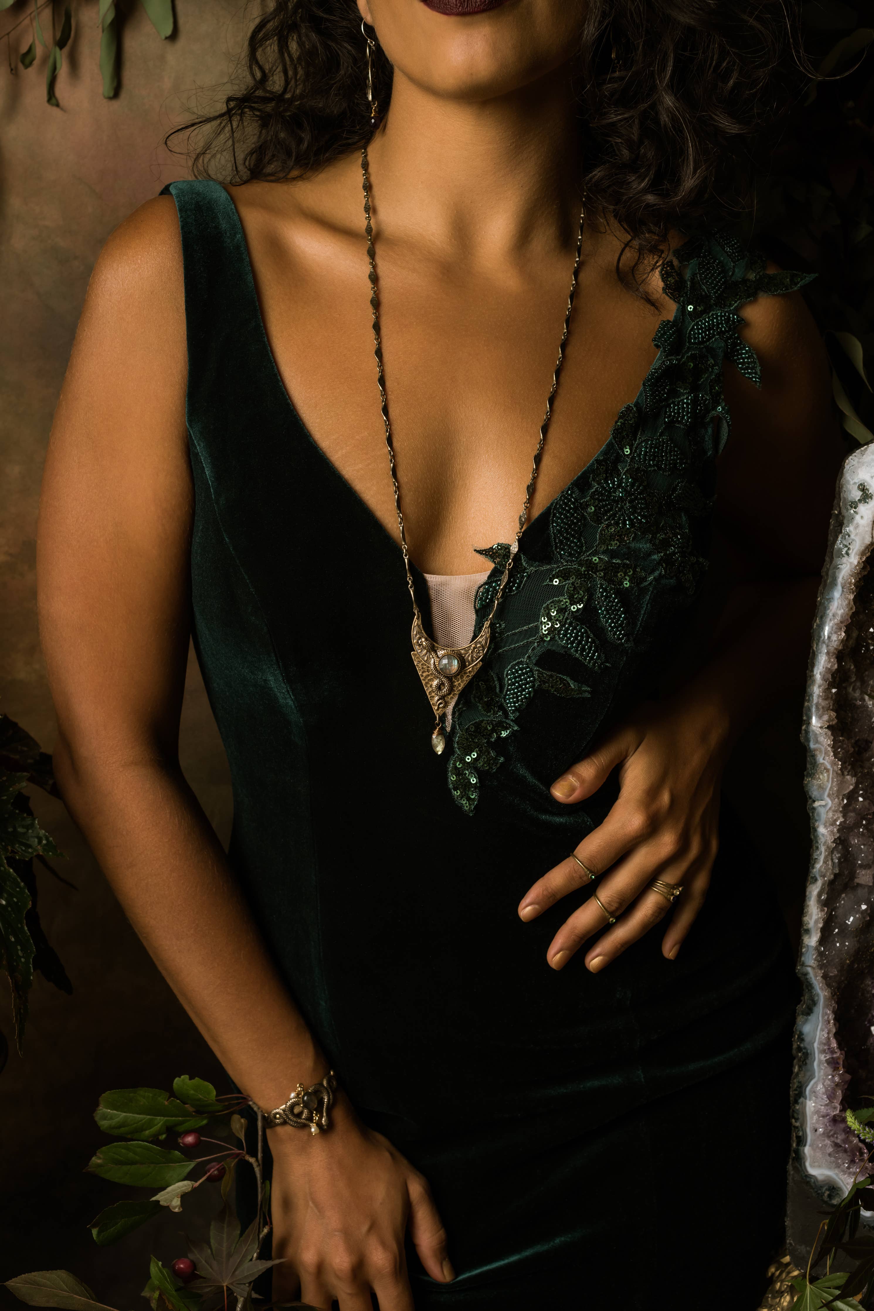 Woman wearing a dark green velvet dress with floral applique and a Moon of Ishtar Pendant Necklace with intricate chain details