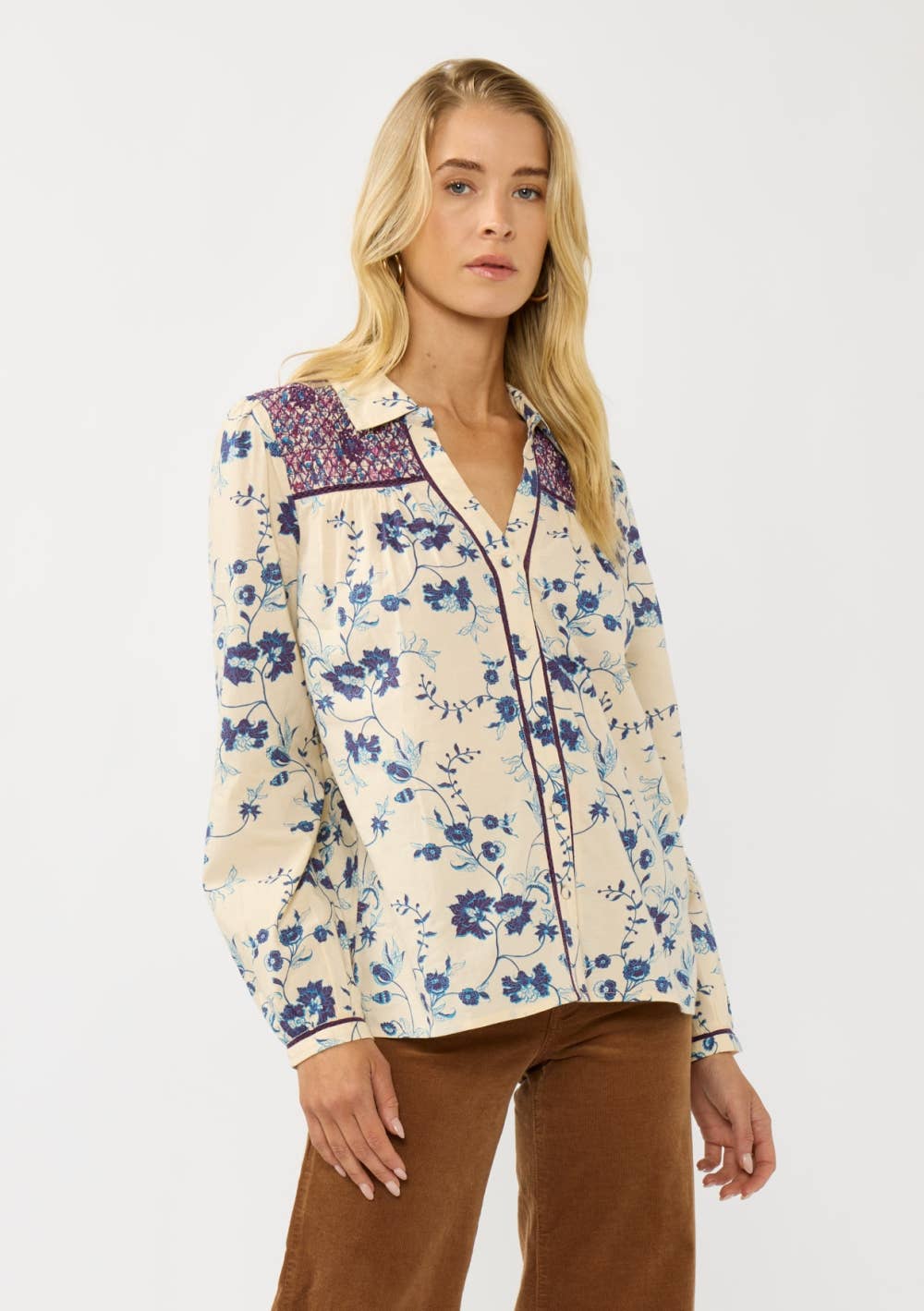Woman wearing a Long Sleeve Floral Blouse with Smocked Yoke featuring blue floral print and contrasting smocked detail.