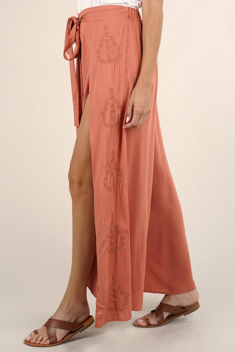 Side view of a terracotta Boho Beach Light Weight Wrap Pant with subtle embroidery and side slit worn with brown sandals