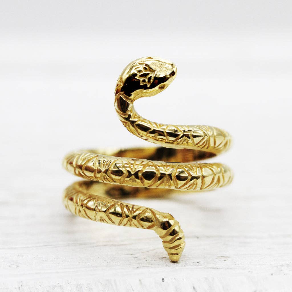 The bahgsu jewels Rattlesnake Lotus Ring is a minimalist piece shaped like a coiled snake with detailed scales and a raised head, displayed on a white surface.
