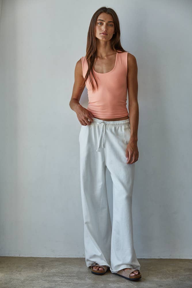 Woman wearing a peach sleeveless Double Layered Seamless Top paired with white wide-leg pants and sandals.