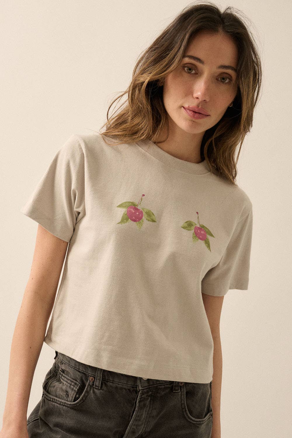 Woman wearing a neutral Cherries Cropped Garment-Dyed Graphic Tee with soft fabric and subtle cherry graphics.