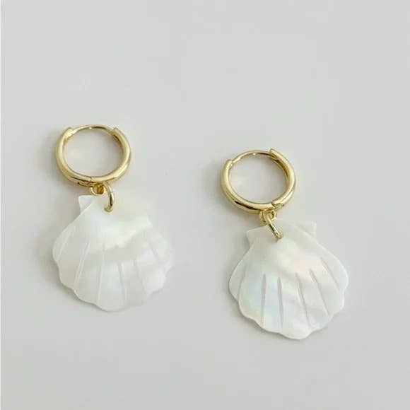 The Scallop Hoop Earrings by Tramps+Thieves feature gold-filled hoops with white, iridescent mother of pearl shell-shaped pendants, shown on a plain light background.