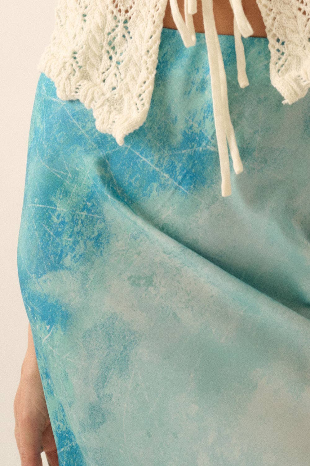 Close-up of a blue textured fabric on a Tie Dye-Print Satin Bias-Cut Maxi Skirt paired with a cream crochet top.