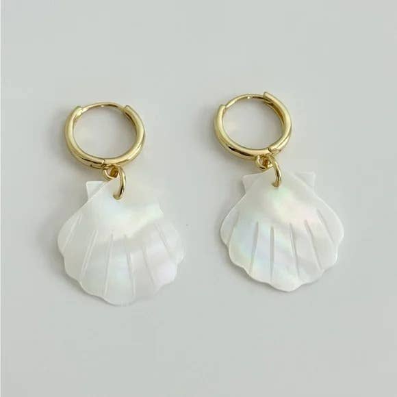 The Scallop Hoop Earrings by Tramps+Thieves feature gold-filled hoops with dangling, iridescent white mother of pearl shell-shaped charms, displayed on a light gray background.