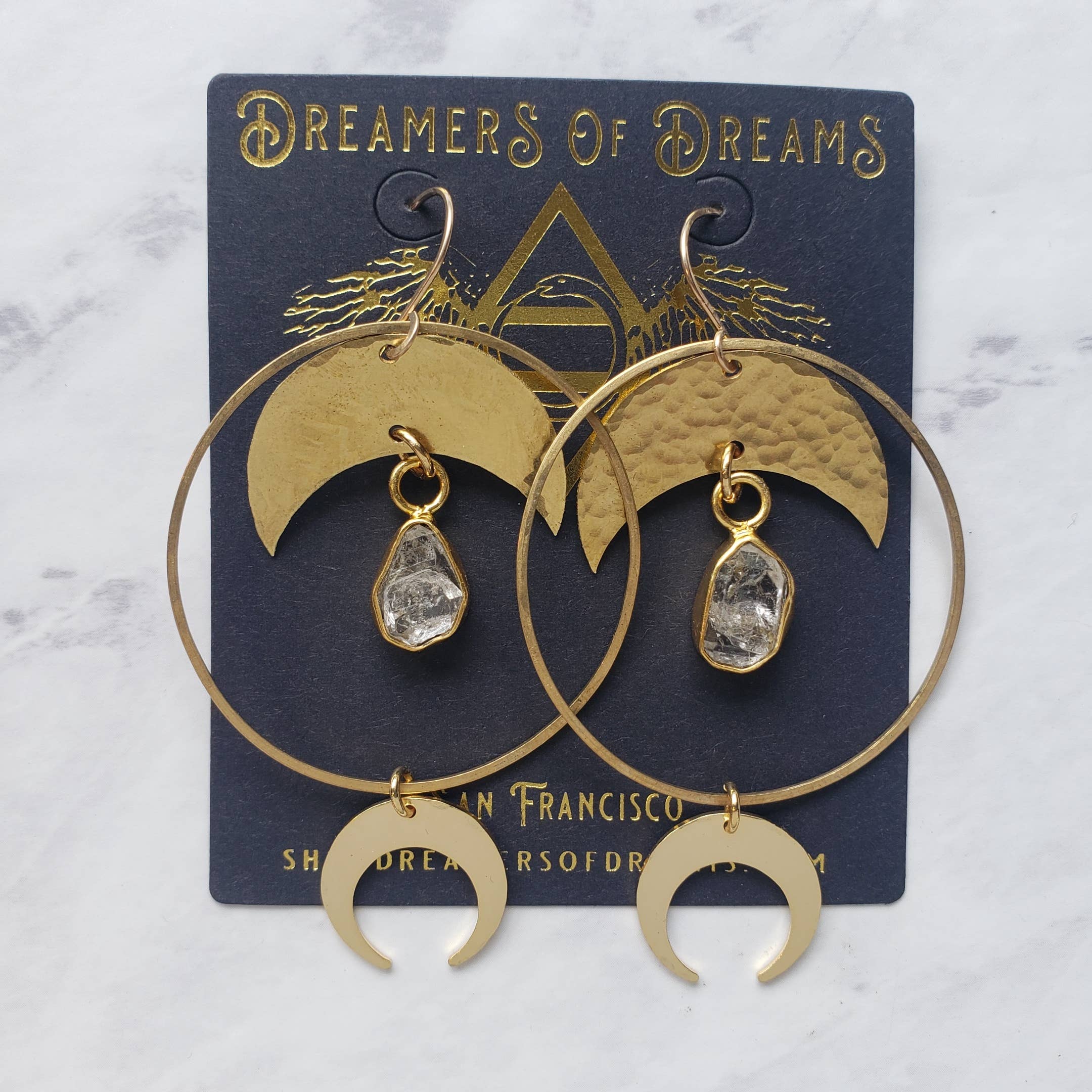 Quartz Halo Moon Hoops featuring crescent moons and rough quartz stones in gold-tone artisan earrings displayed on branded card
