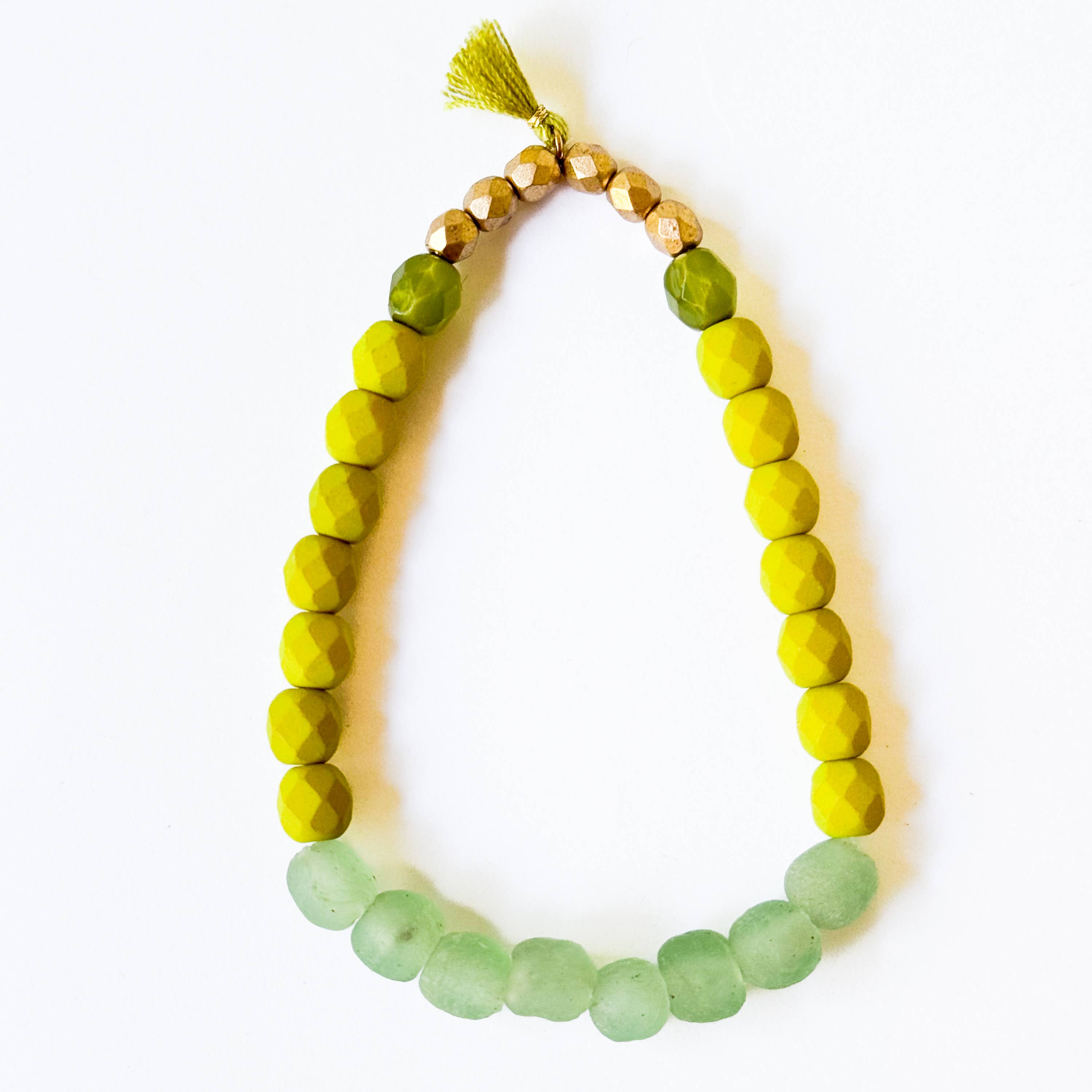 Multicolor Recycled African Glass And Mixed Bead Bracelet with green, yellow, and gold beads and a small tassel centerpiece