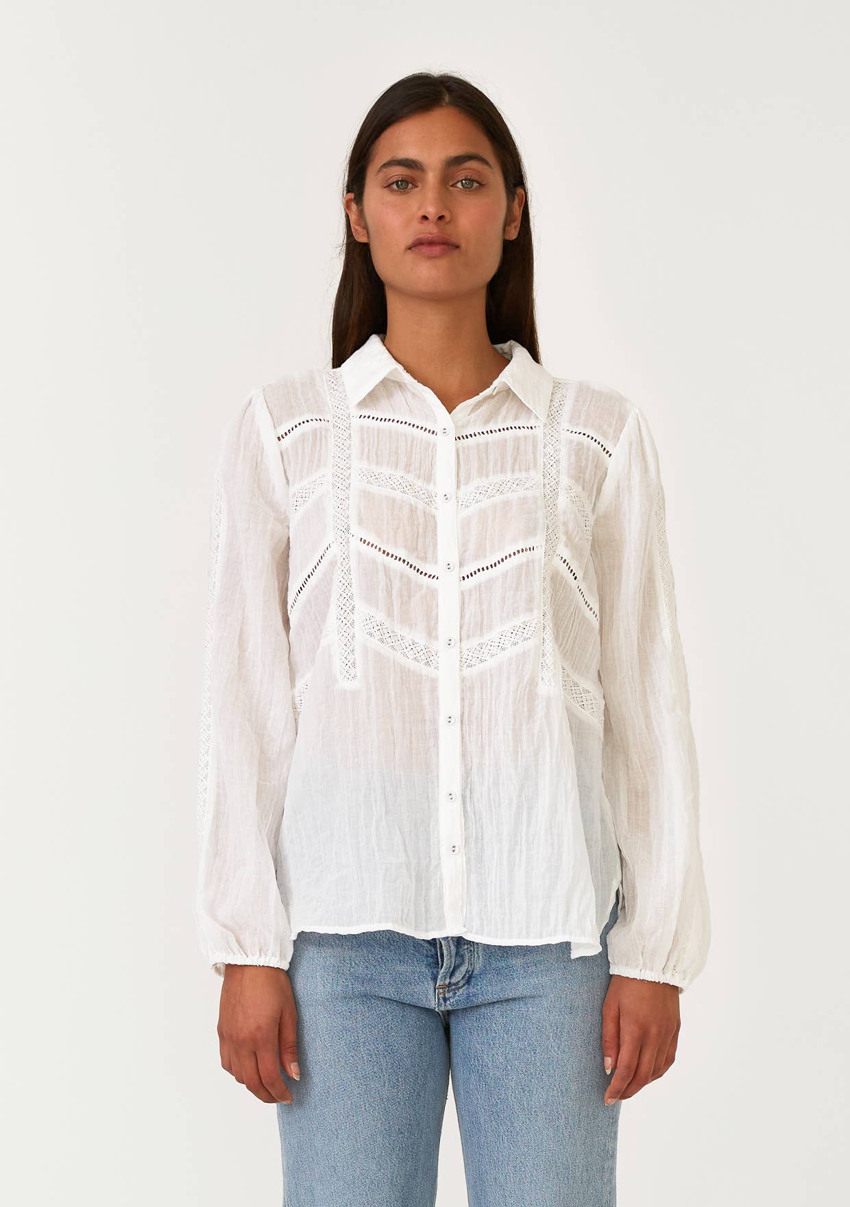 Woman wearing a white Crinkled Lace Long Sleeve Button Down Blouse with delicate lace details and light blue jeans
