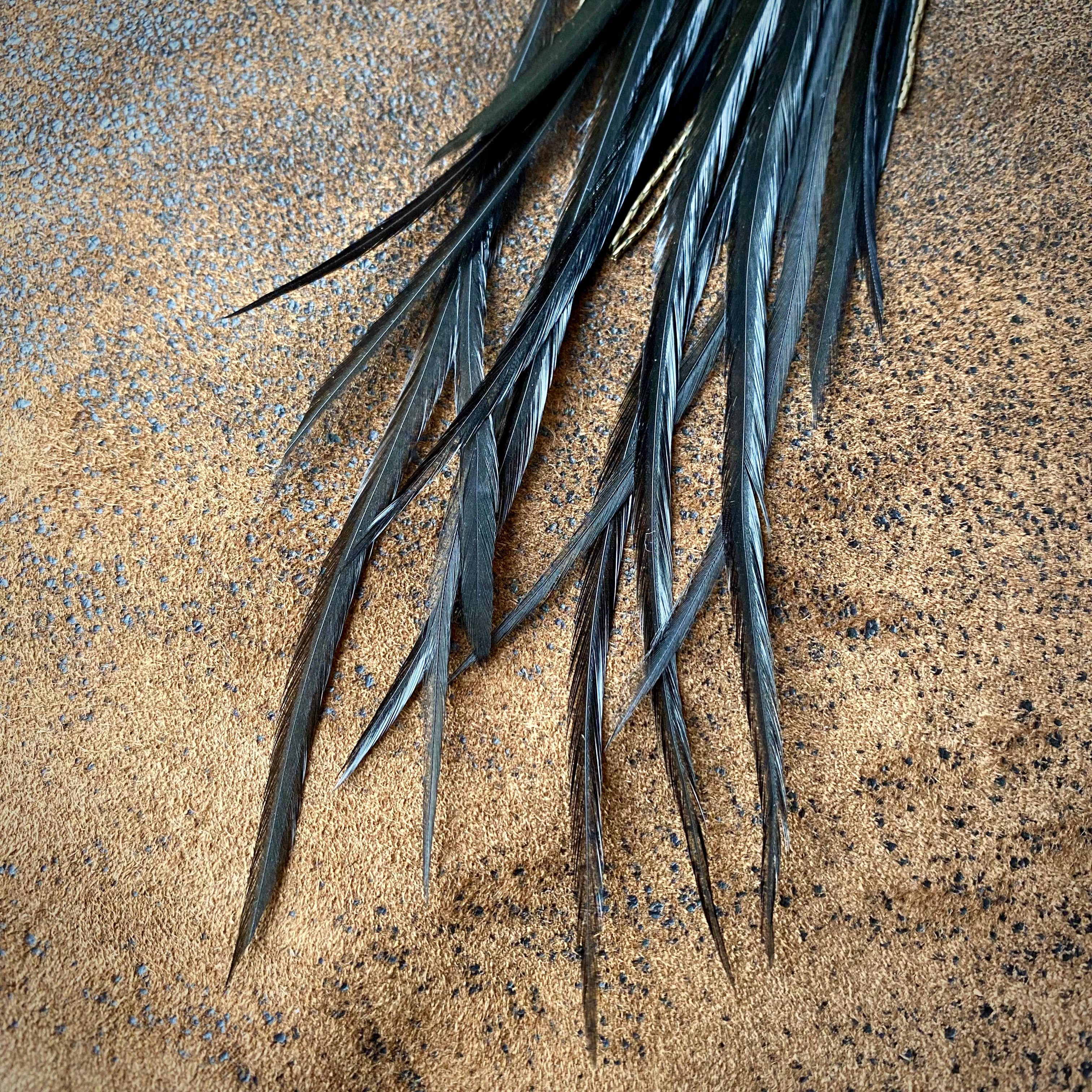 Close-up of long, thin dark green leaves on a textured surface; ASTALIs Feather & Turquoise Statement Earrings—Antique Brass & Sustainable Coque Feathers—would make a striking pairing with this natural backdrop.