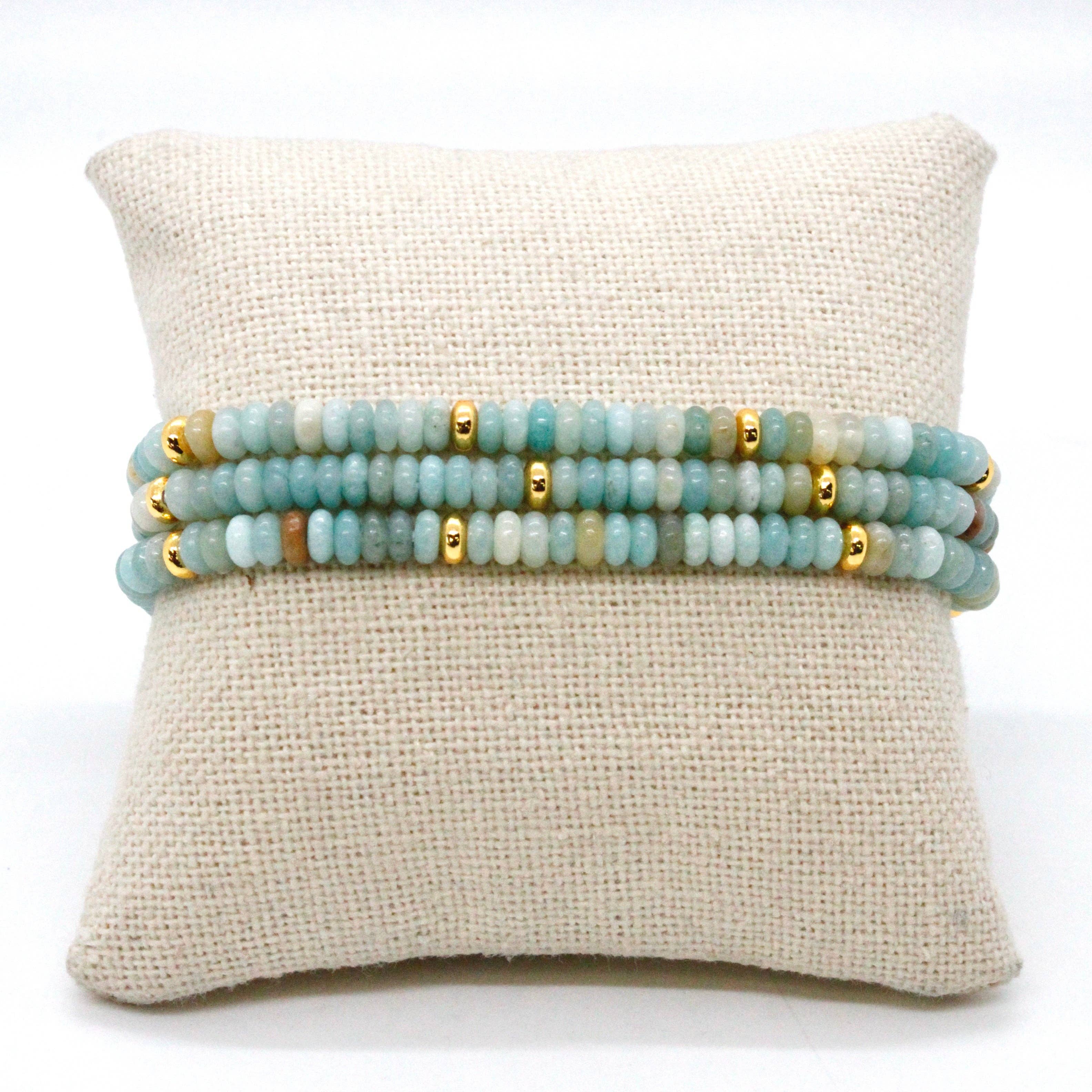 Amazonite + Gold Bracelet Bundle featuring soft blue-green beads with gold accents displayed on a beige cushion