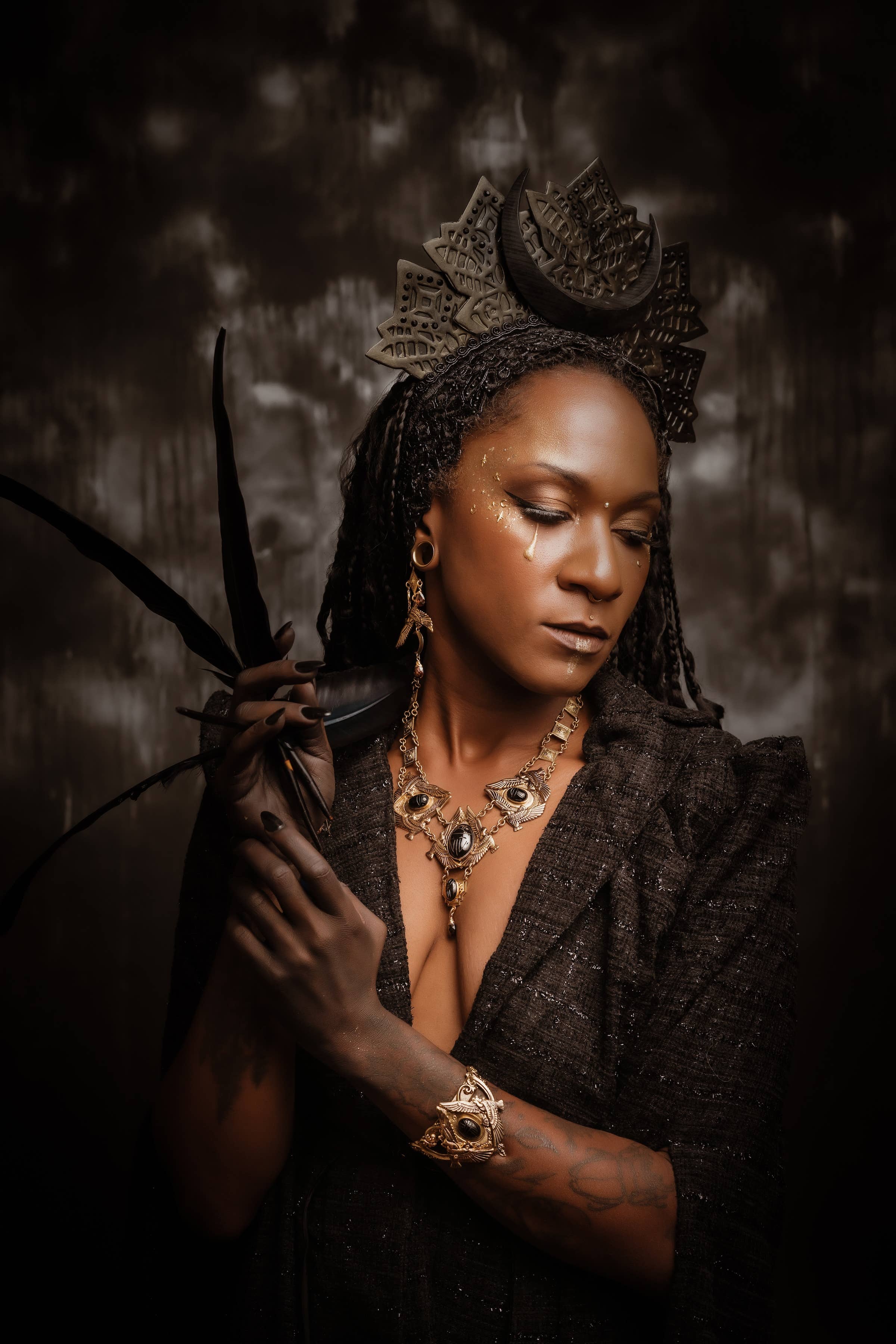 Woman wearing intricate headpiece and gold jewelry including the Nekhbet Shield Cuff bracelet in artistic portrait