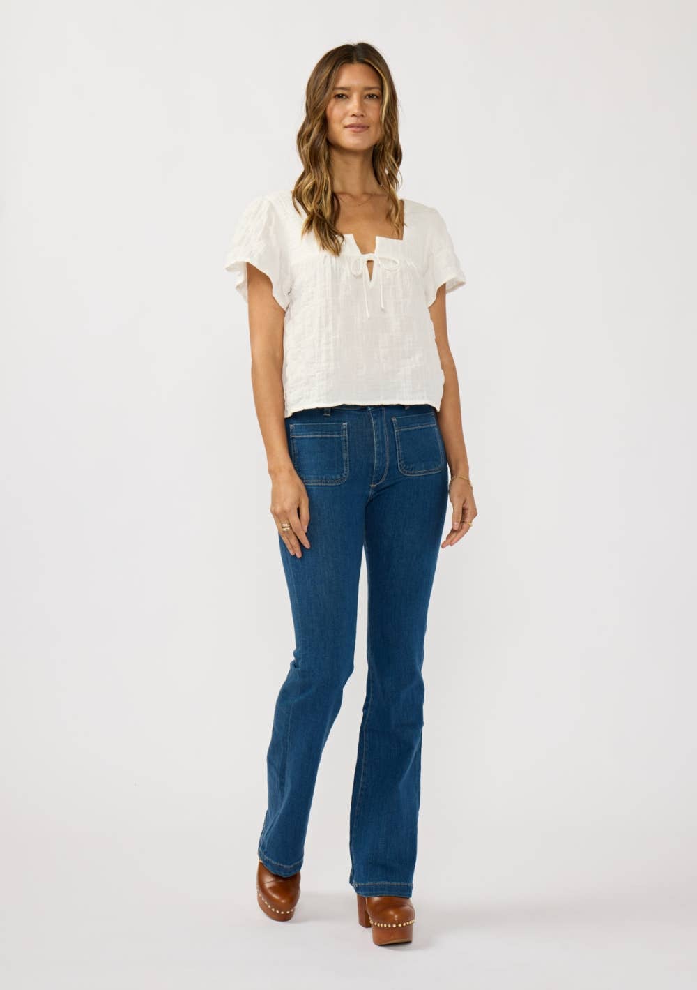 Woman wearing a Square Neck Puff Sleeve Gauze Top in white paired with blue jeans and brown clogs against a plain background
