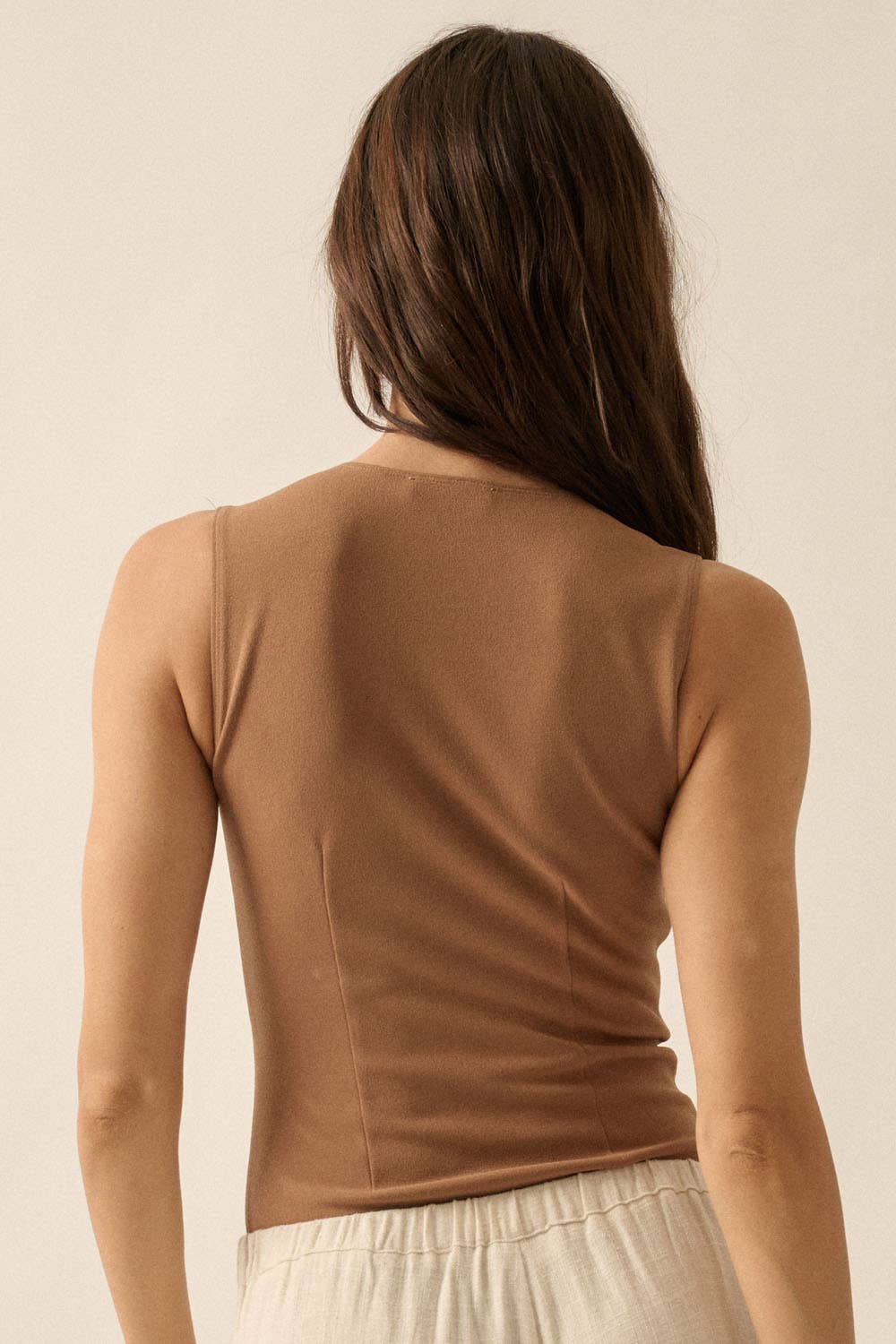Back view of woman wearing a tan Essential Trends Crepe V-Neck Bodysuit paired with light-colored pants