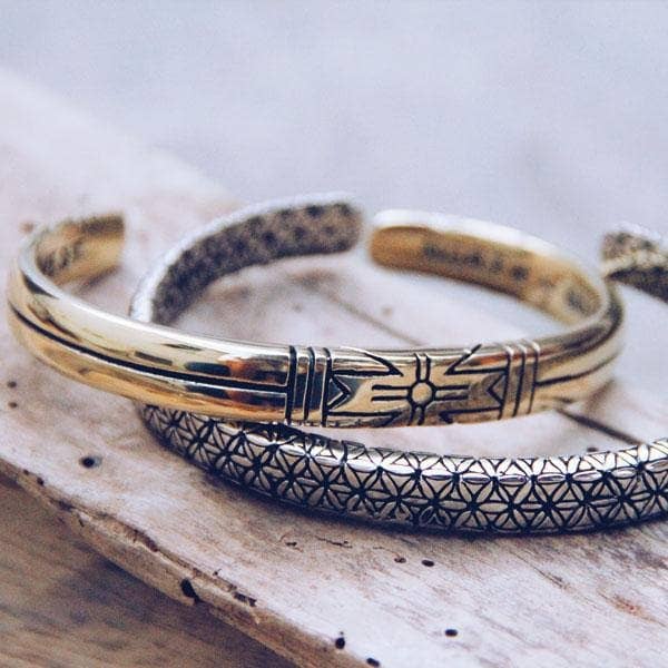 Medicine Wheel Cuff || Men displayed with intricate geometric and symbolic engravings on a rustic wooden surface.