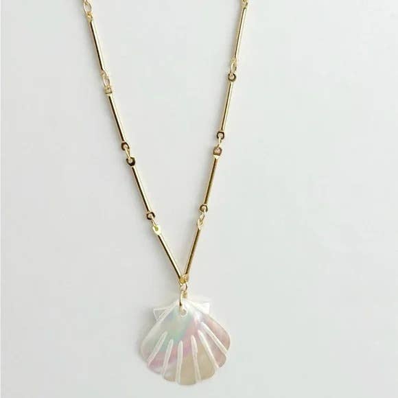The Muna Shell Necklace by Tramps+Thieves features a shiny, iridescent mother of pearl shell pendant on a gold chain, elegantly displayed against a plain white background.