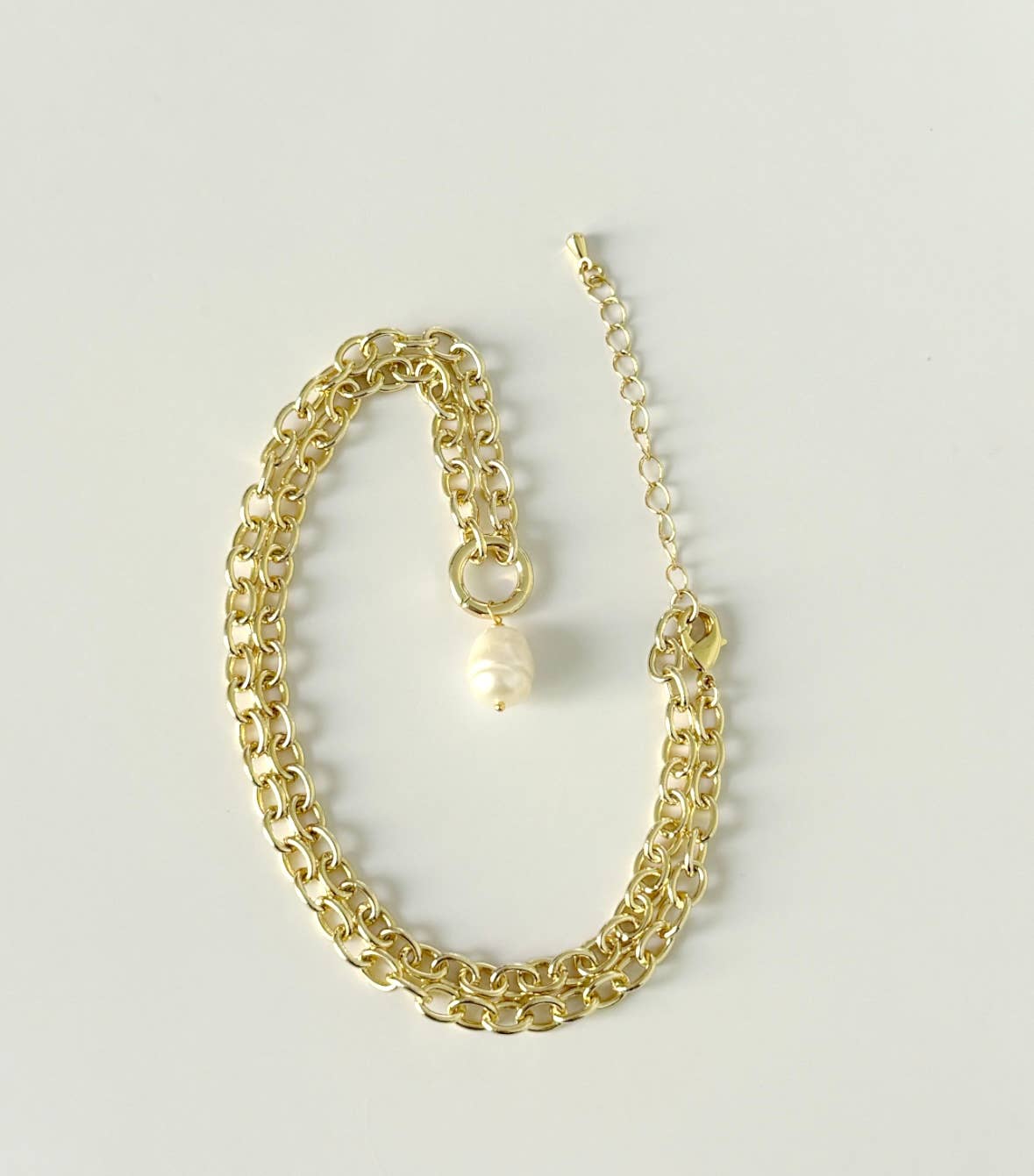 A Los Angeles jewelry staple, the Tramps+Thieves Soizic Necklace features 18K gold plating, a single baroque pearl charm, and an adjustable clasp, shown on a light neutral background.