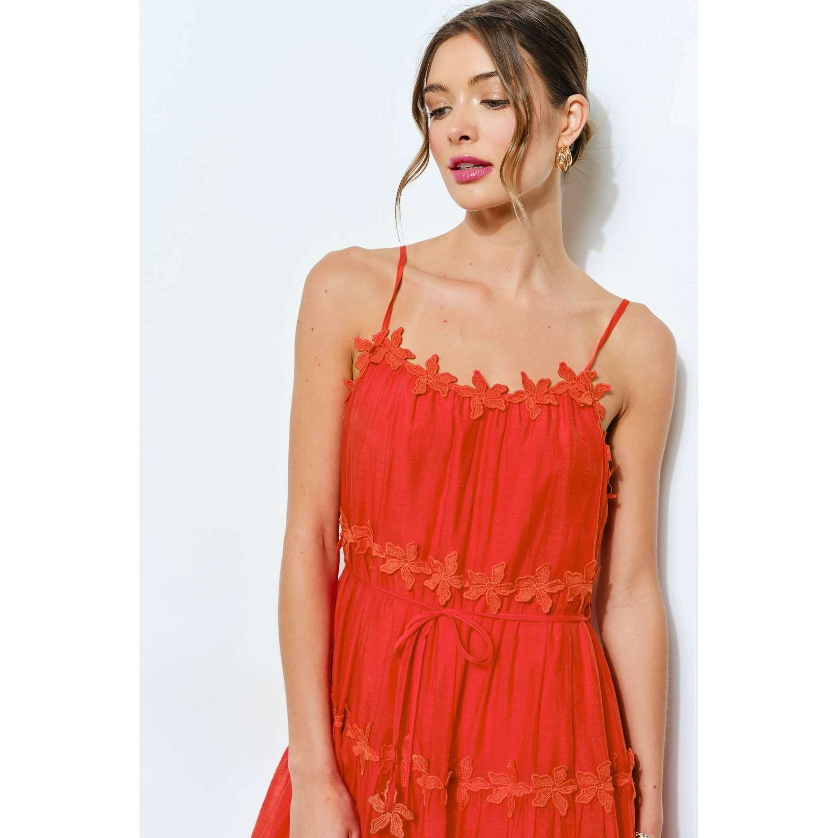 Woman wearing a red dress with floral details against a white background