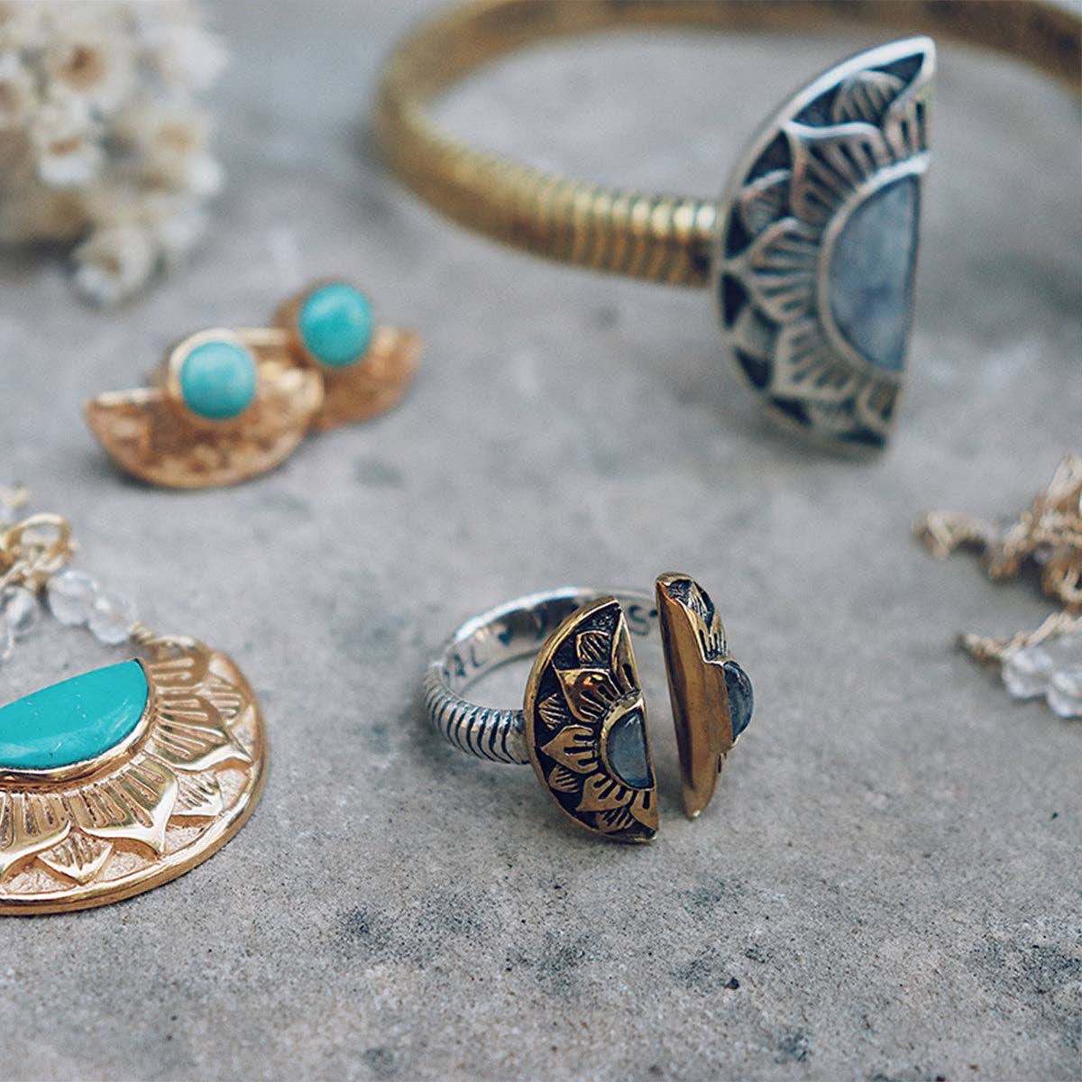 Assorted boho jewelry, including earrings, bracelets with sun and crescent moon designs, and the bahgsu jewels Natural Mystic Ring - Moonstone with turquoise and gold accents, are beautifully displayed on a stone surface.