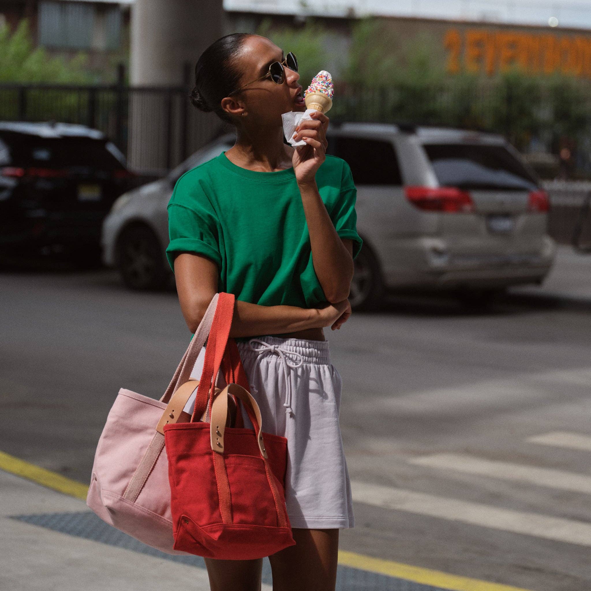 Woman wearing green shirt holding ice cream cone and carrying a red Lunch Tote | Persimmon with leather handles outdoors