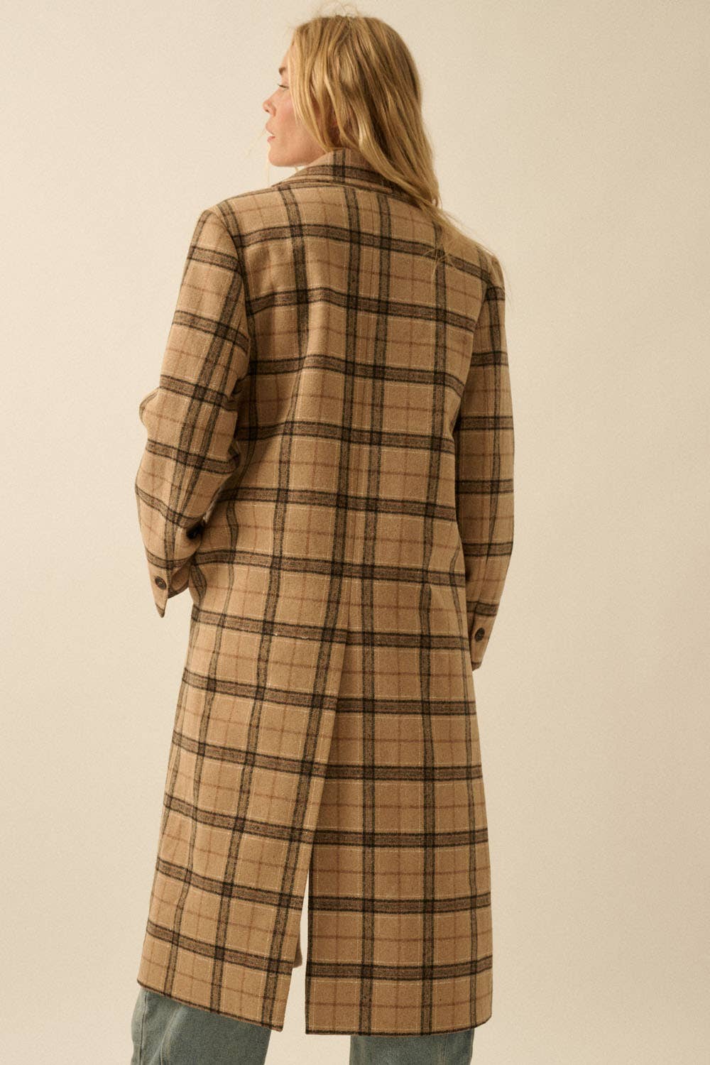 A person with long blond hair wears the Promesa USA Plaid Felt Double-Breasted Calf-Length Overcoat, featuring tan fabric with black and brown lines, standing back to the camera against a neutral background.