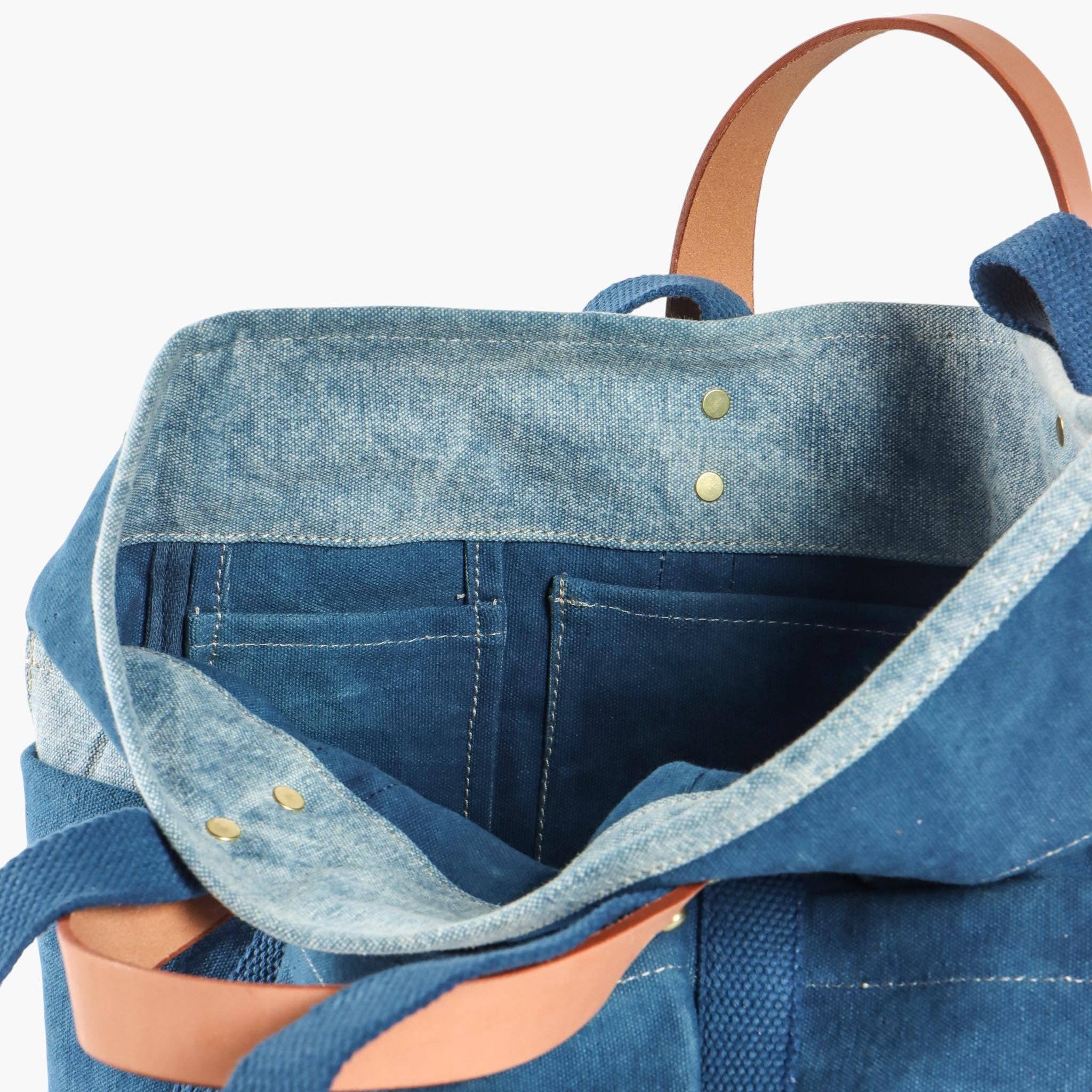 Blue denim backpack with leather handle on a white background