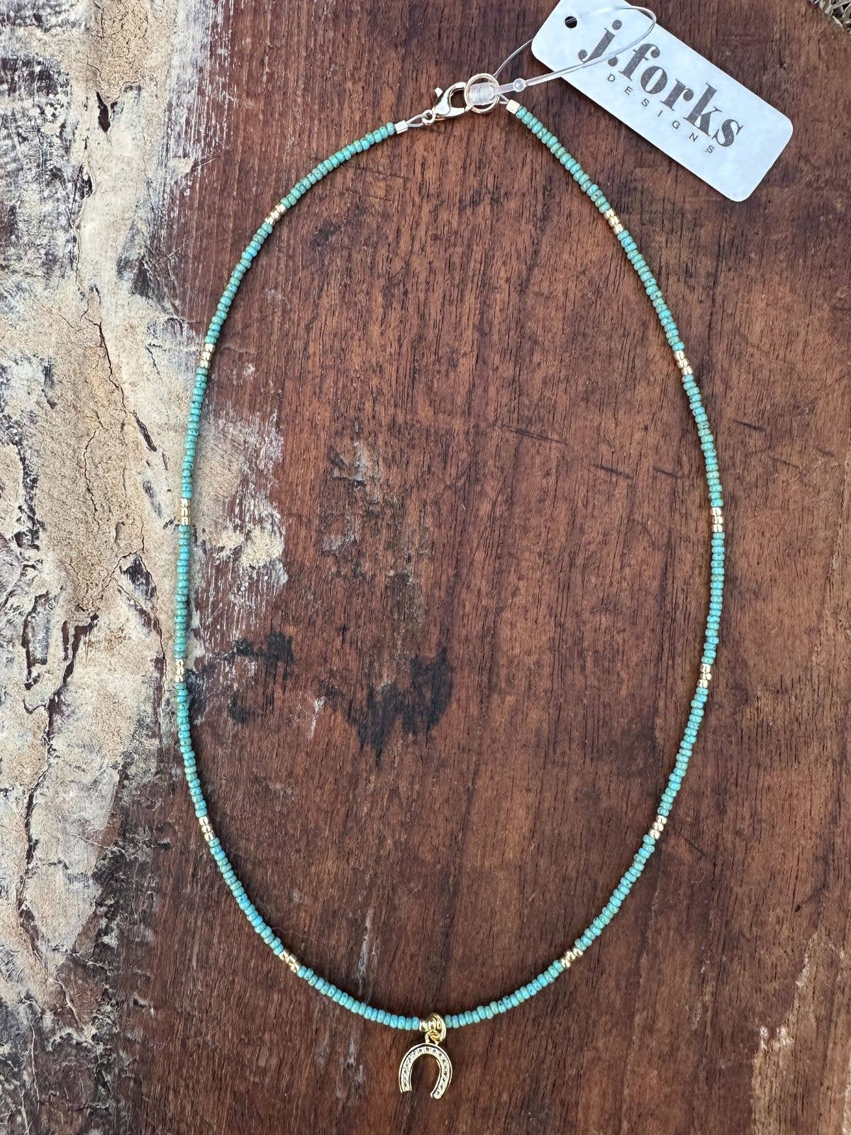 17892 Turquoise Seed Bead & Horseshoe Charm Necklace with gold accents on rustic wooden background