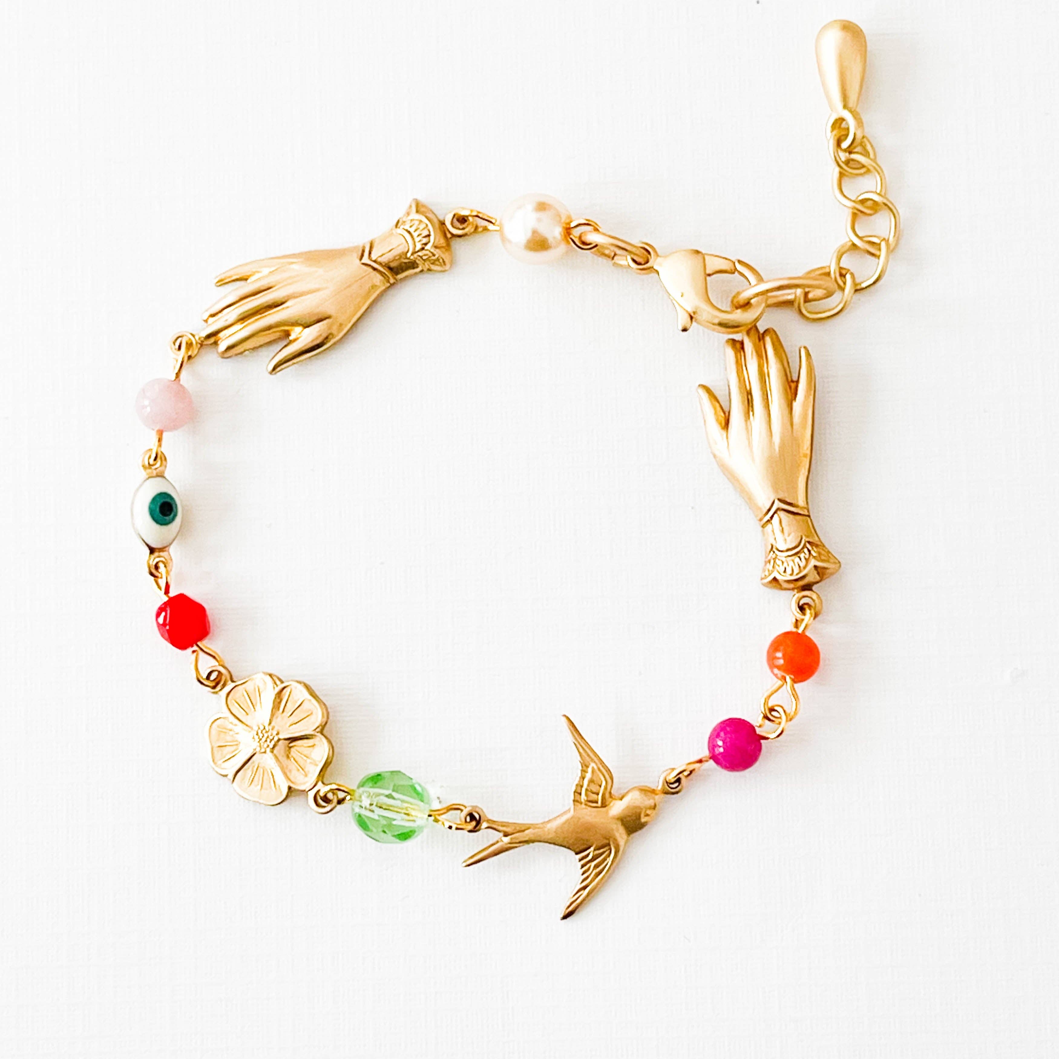 Adjustable Evil Eye Charm Bracelet With Pearl And Beads featuring gold hand charms, colorful beads, and a small bird charm on white background